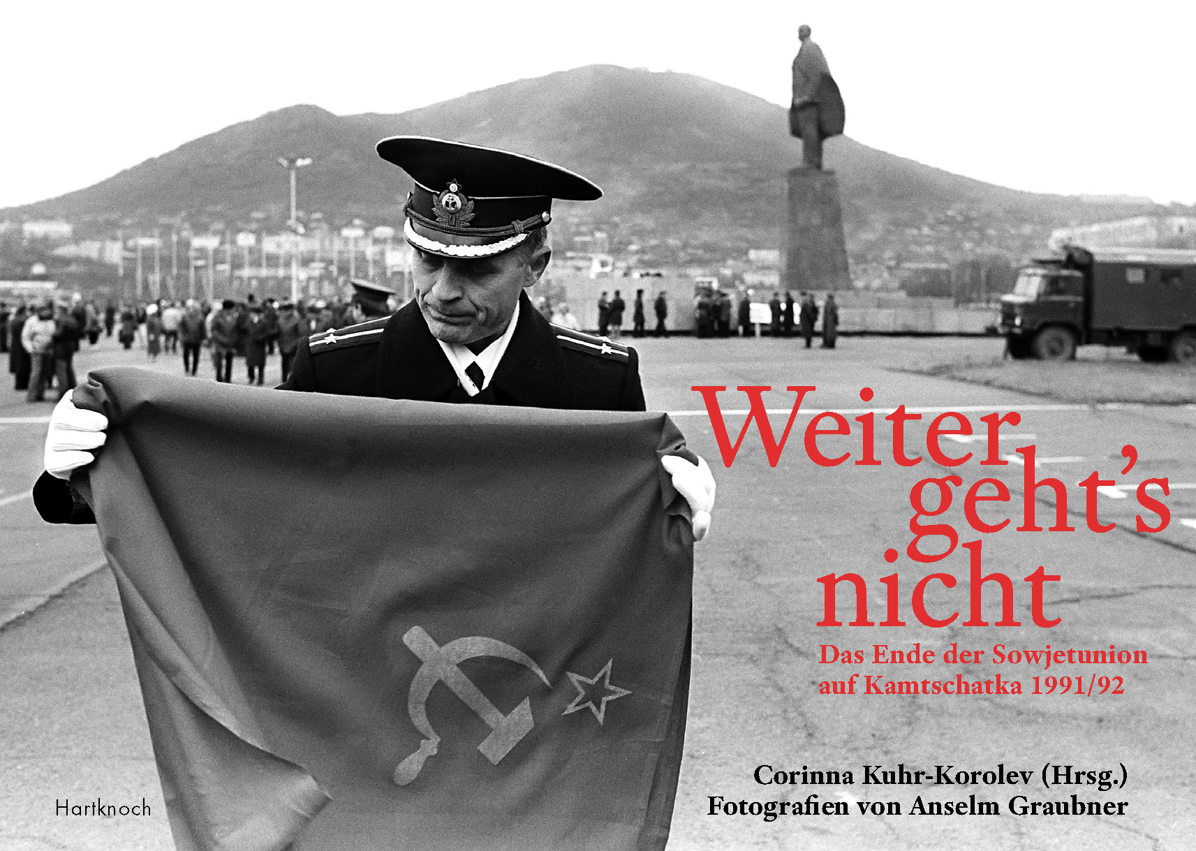 Das Bild zeigt einen Soldaten, der auf einem weitläufigen Platz eine Flagge zusammenfaltet.