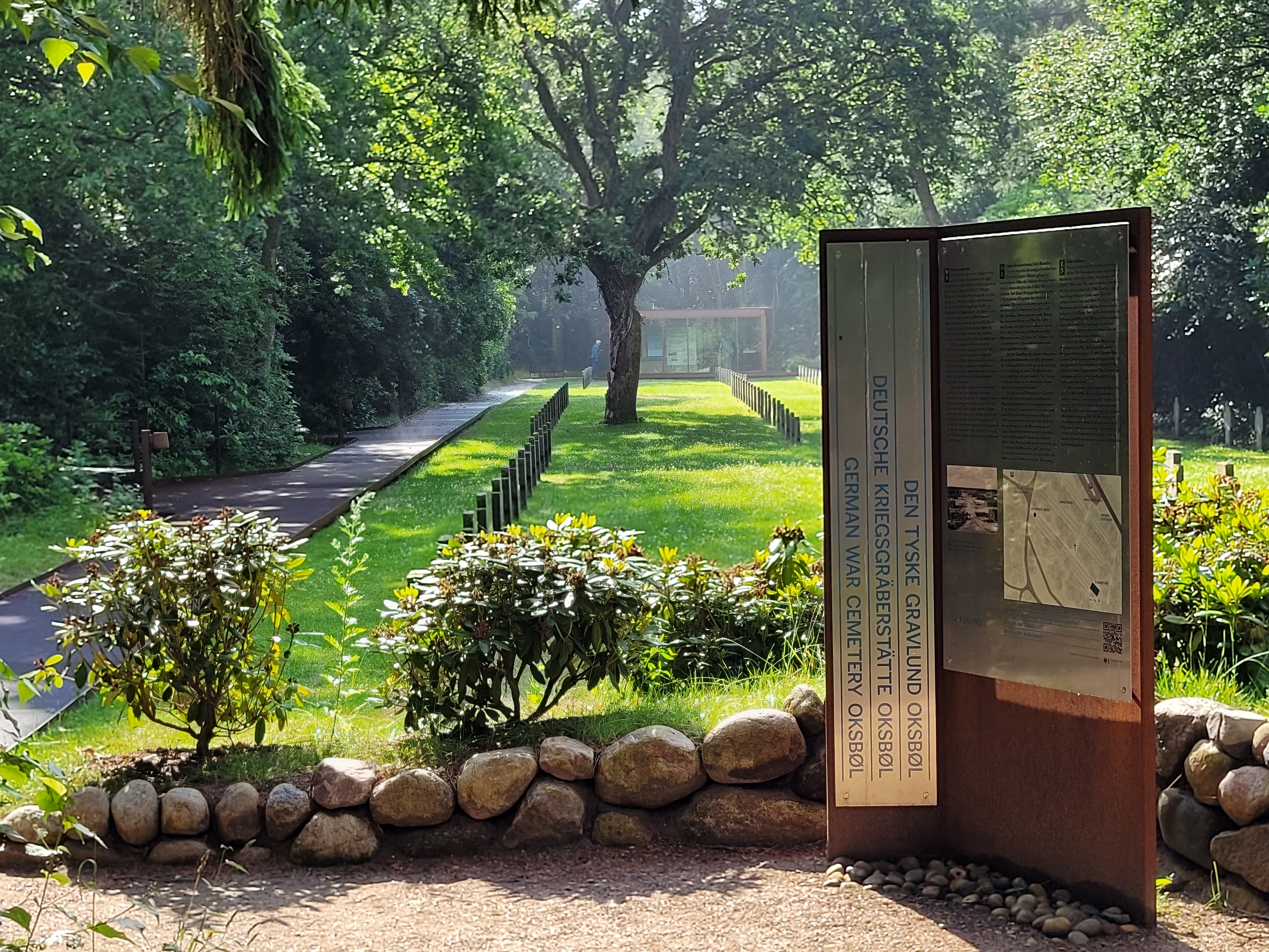 Blick auf den Flüchtlingsfriedhof der Kriegsgräberstätte in Oksbøl in Dänemark vom Gebäude der Dauerausstellung aus. Im Vordergrund istv eine Tafel der Dauerausstellung zu sehen, die im Julki 2026 eröffnet wurde..