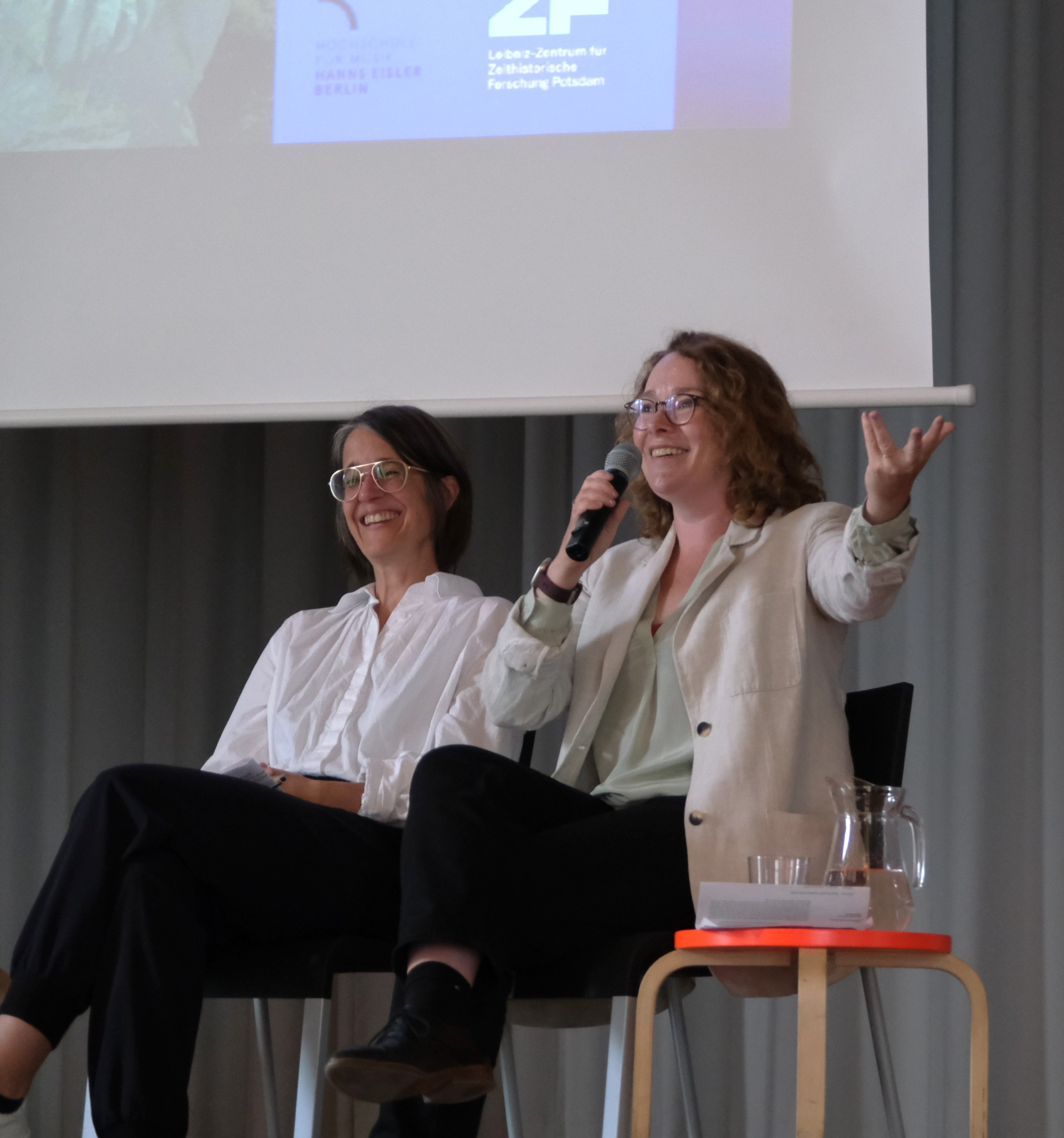 Das Foto zeigt der Andrea Tober (links) und Anna Luise Kiss (rechts) auf dem Podium in der Aula der weißensee kunsthochshule Berlin während des Symposiums "Kulktur im Umbruch" am 4.6.2026.. 