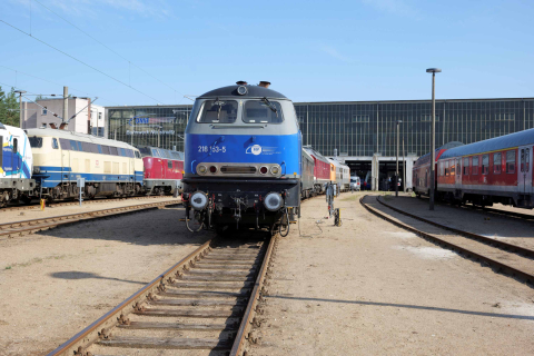 Eine blau lackierte Lokomotive steht vor einem Betriebsgebäude in Neustrelitz.