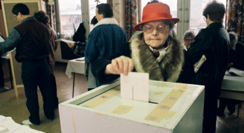 Titelbild des ZZF Jahresberichts 2024. Auf dem Titelfoto ist eine ältere Frau mit rotem Hut zu sehen, die in einem Wahlbüro einen Stimmzettel in eine Wahlurne wirft.