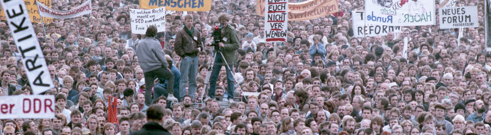 Foto einer großen Menschenmenge bei einer Demonstration am 4. November 1989. Viele der Menschen tragen Plakate und Transparente.