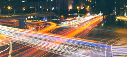 Aufnahme einer verkehrsreichen Kreuzung in Taipei bei Nacht, durch die lange Belichtungszeit hinterlassen die Lichter der Fahrzeuge rote und weiße Spuren.