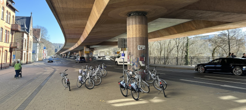 Berliner Stadtautobahn in unmittelbarer Nähe von Wohnhäusern. Unter der Trasse findet der Verkehr von Pkw, Fährrädern und Fußgänger*innen statt.